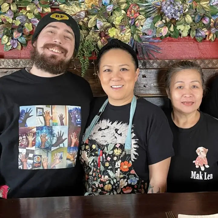 Our founders, Chuckie Brown-Soukaseume (left) and Chef Jamie Brown-Soukaseume (right), smiling behind the bar at Ahan
